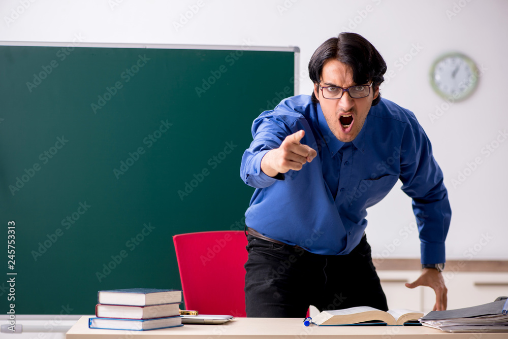 Young male teacher in front of chalkboard Young male teacher in front of chalkboard