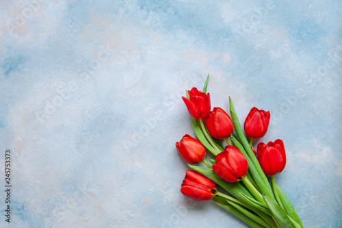 Bouquet of red tulips. Concept for Valentine's Day, womens day and other romantic events. Top view, close-up, flat lay on blue background