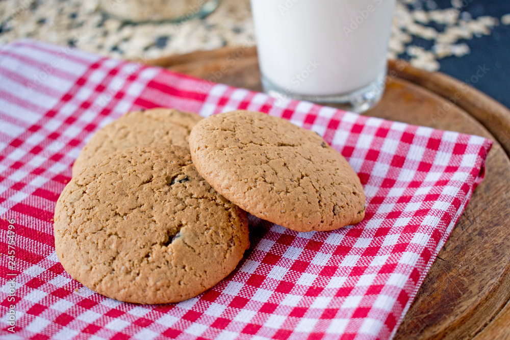 oatmeal cookies with glass of milk on tablecloth and wooden board oatmeal cookies with glass of milk on tablecloth and wooden board