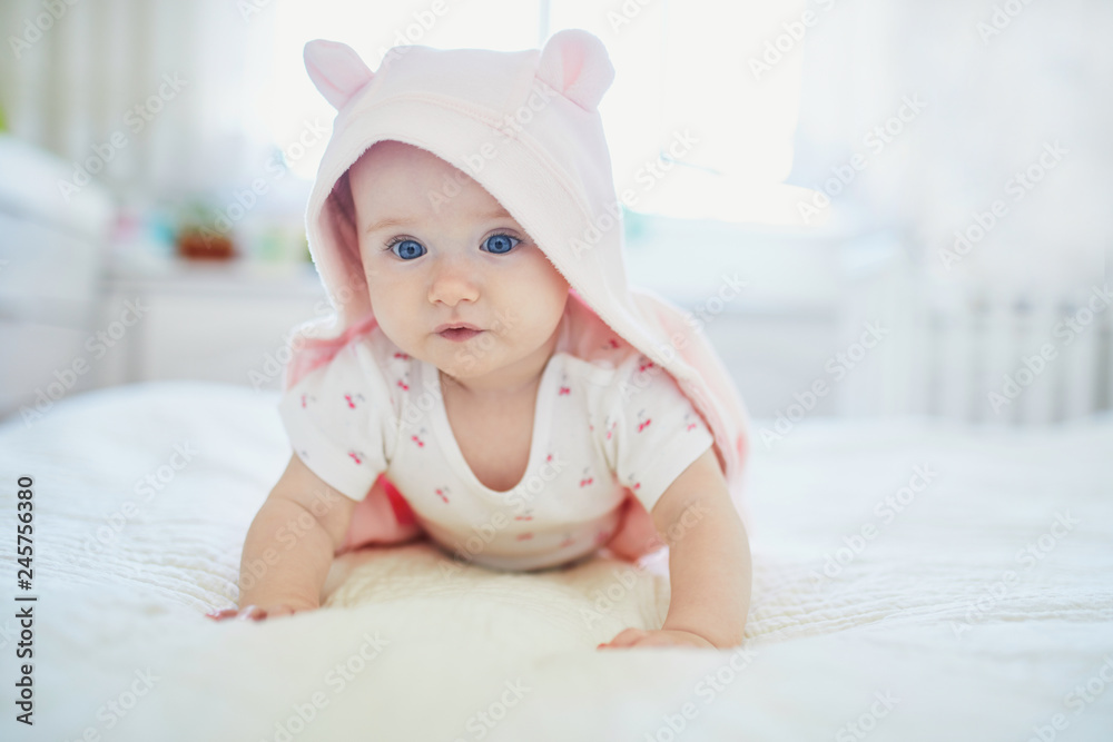 baby girl relaxing in bedroom in pink clothes or towel with ears baby girl relaxing in bedroom in pink clothes or towel with ears