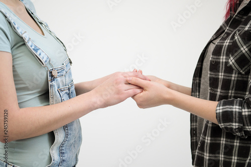 Two girls in jeans hold hands close up. White background. Homosexual lesbian couple. © spaskov