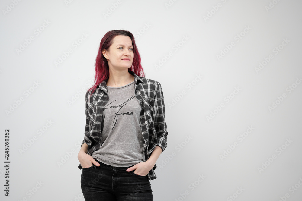 The girl in a plaid gray shirt on a white background with dyed red hair. The girl in a plaid gray shirt on a white background with dyed red hair.