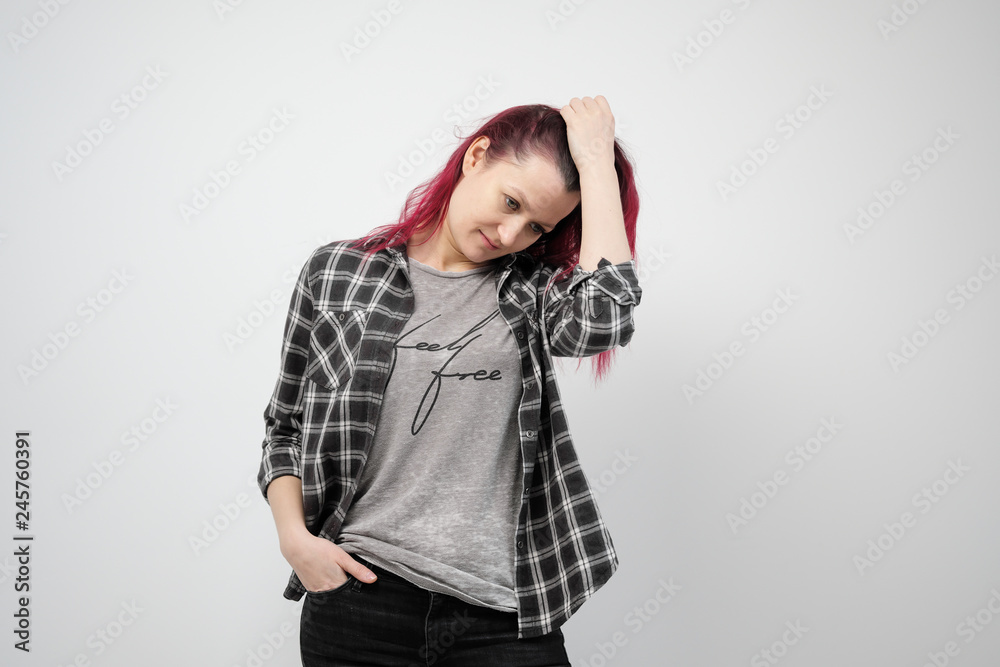 The girl in a plaid gray shirt on a white background with dyed red hair. The girl in a plaid gray shirt on a white background with dyed red hair.