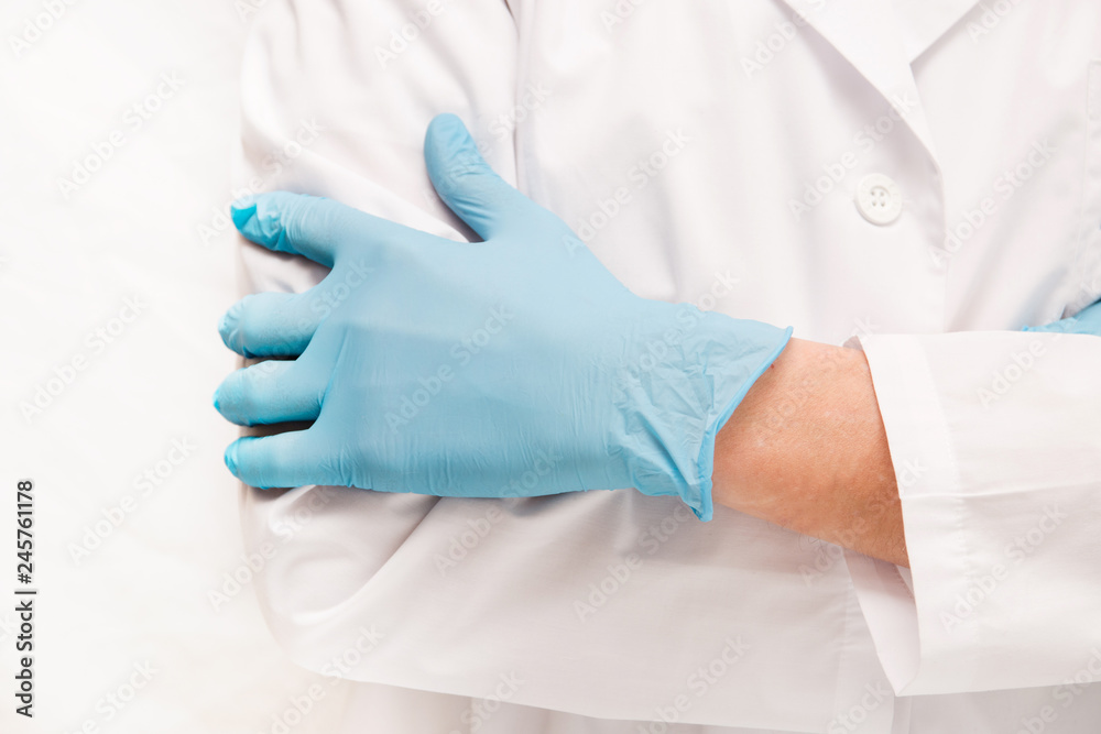 Fototapeta premium man doctor in blue medical gloves on while standing against a white background