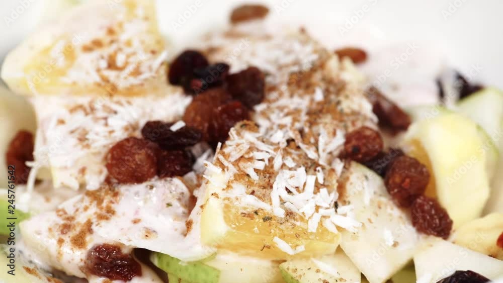 Mixed and assorted fruits in bowl rotating. Healthy salad dessert. Kiwi, orange, pear and banana slices with yoghurt and raisins. Healthy nutrition Mixed and assorted fruits in bowl rotating. Healthy salad dessert. Kiwi, orange, pear and banana slices with yoghurt and raisins. Healthy nutrition