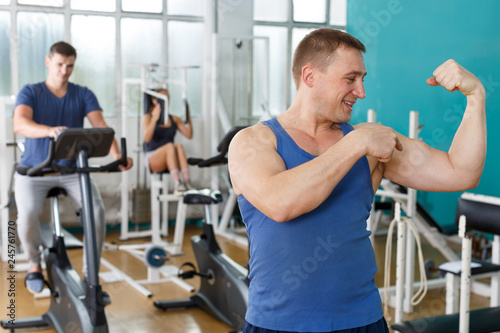 Guy posing among sports equipment at gym