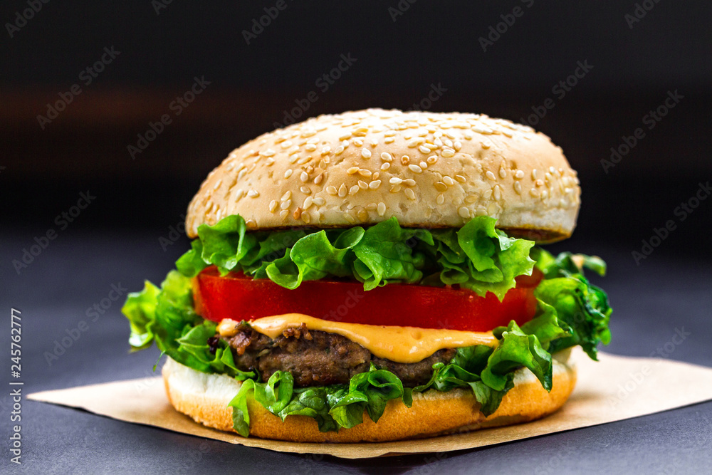 Delicious fresh homemade burger on a dark background. Fast and bad food