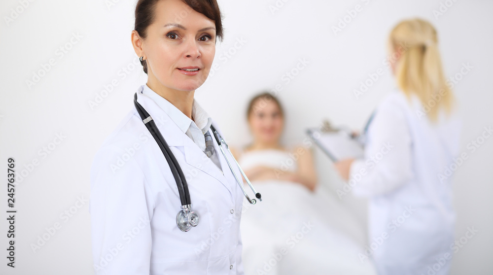 Female doctor at the background with patient. Physician at work Female doctor at the background with patient. Physician at work