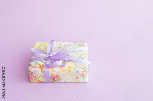 Wrapped gift box with purple ribbon. © alexngm