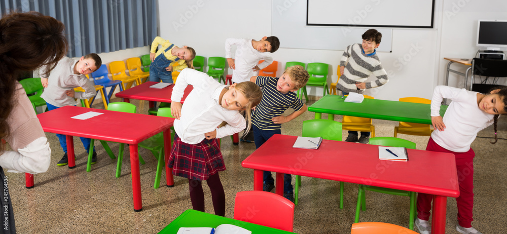 Fotografie Schoolchildren with teacher performing physical exercises