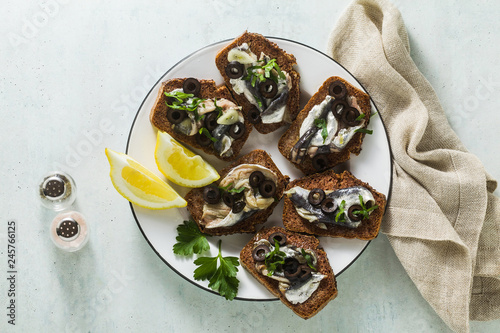 sandwiches with sardines marinated in olive oil with garlic and rye bread. summer light italian appetizer with lemon and parsleylive oil with garlic and rye bread. summer light italian appetizer
