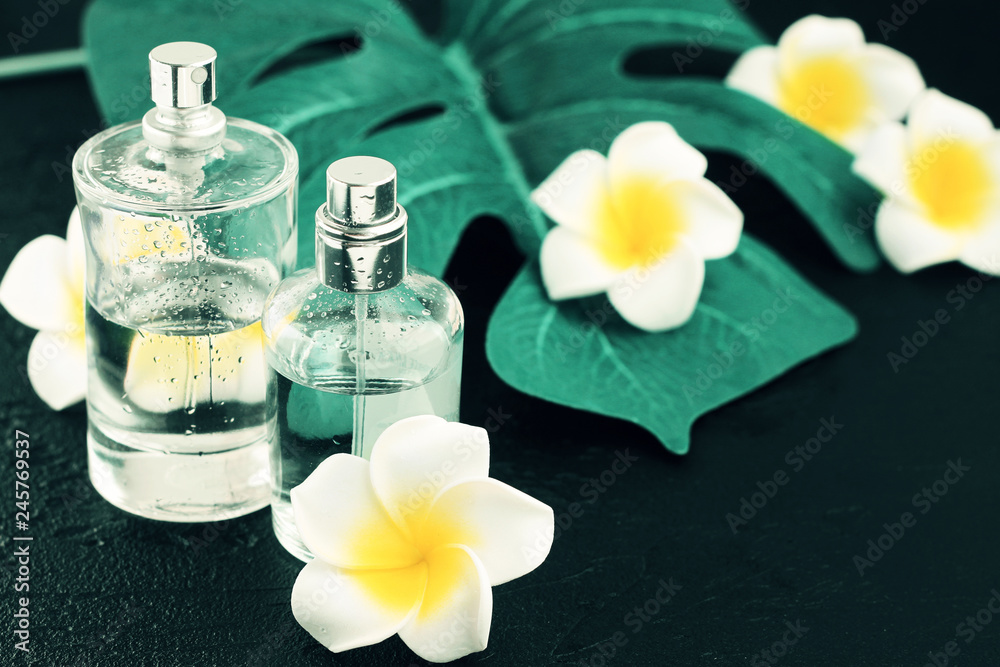 Perfume spray bottles on black table with green plant decor leaf and tropical flowers, spa & massage background.
Perfume spray bottles on black table with green plant decor leaf and tropical flowers, spa & massage background.