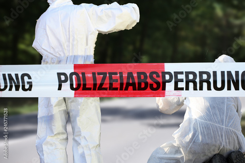 Polizeiabsperrung mit Spurensicherung im Hintergrund photo