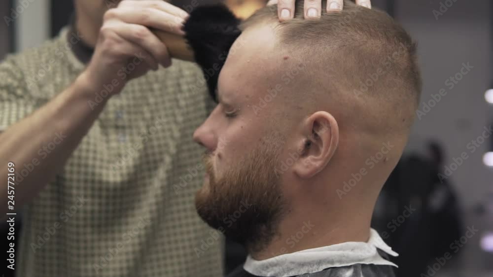 Male barber trimming beard with shaver. Barber shaving beard with electric razor and comb in male salon Male barber trimming beard with shaver. Barber shaving beard with electric razor and comb in male salon