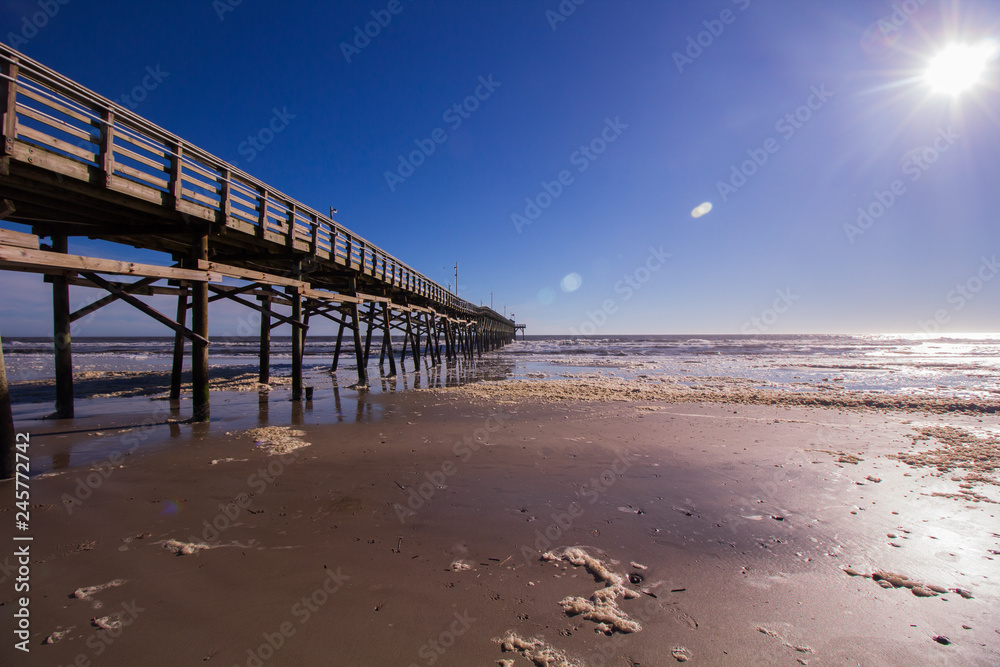 Sun shining on fishing pier and beach Sun shining on fishing pier and beach