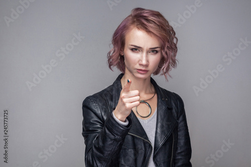 Schilderij op canvas Portrait of caution serious beautiful girl with short hairstyle and makeup in casual style black leather jacket standing, warning and looking camera