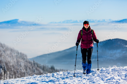 Woman trekking traveler with backpack hiking in Beskidy mountains at sunny day, adventure concept active vacations with outdoor activity on snow in the forest, Poland- Image
