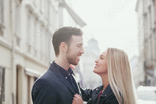 Happy embracing couple posing in street of european city. Models look at each other. Copy, empty space for text