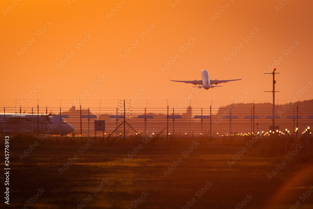 Plane on the track preparing to take off at sunset with red sky in background in same time with other taking off Plane on the track preparing to take off at sunset with red sky in background in same time with other taking off