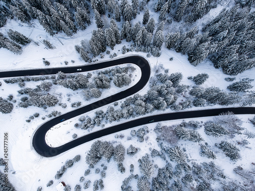 View from up of beautiful curve road in the middle of a forest full of snow in winter time.