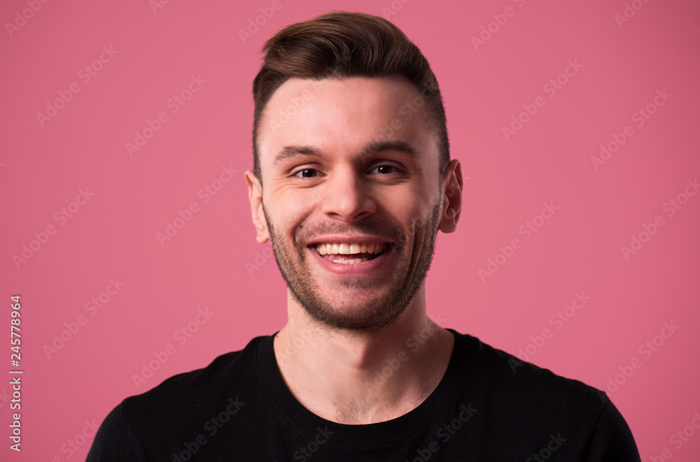 Happy handsome young man portrait in black t-shirt isolated on pink wall Happy handsome young man portrait in black t-shirt isolated on pink wall