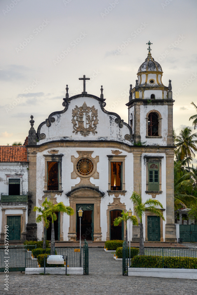 The historic architecture of Olinda in Pernambuco, Brazil showcasing The Mosteiro de Sao Bento church with its Baroque facade and cobble stone pathway on a sunny day.