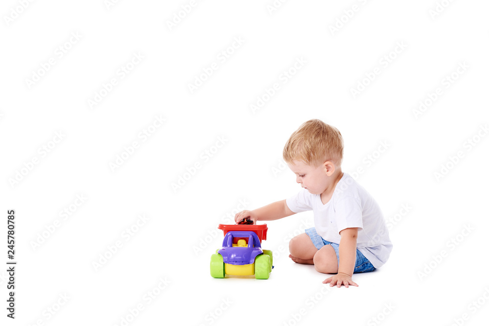 Cute boy plaing with toy car on floor, isolated on white