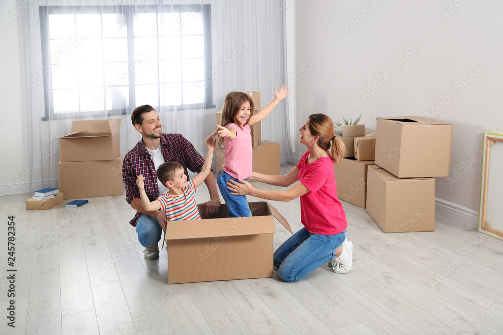 Happy family playing with cardboard box in their new house. Moving day Happy family playing with cardboard box in their new house. Moving day