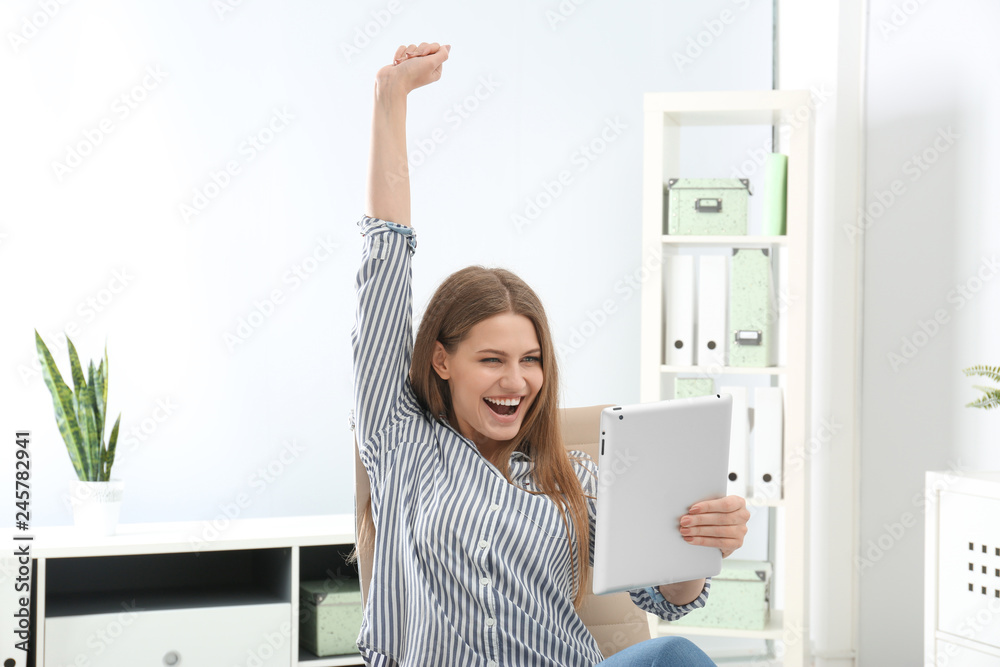 Emotional young woman with tablet celebrating victory in office Emotional young woman with tablet celebrating victory in office