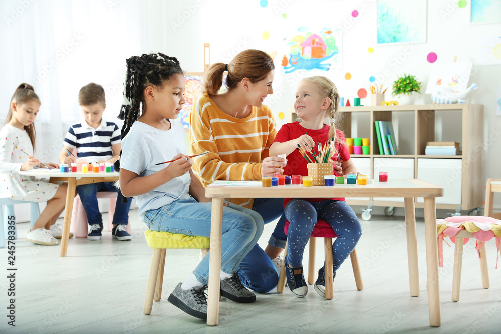 Fototapeta premium Children with female teacher at painting lesson indoors