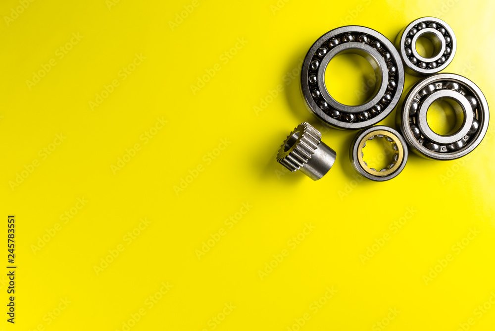 Ball bearing lying on a yellow background with copy space on the left side. Flat view from above. Ball bearing lying on a yellow background with copy space on the left side. Flat view from above.