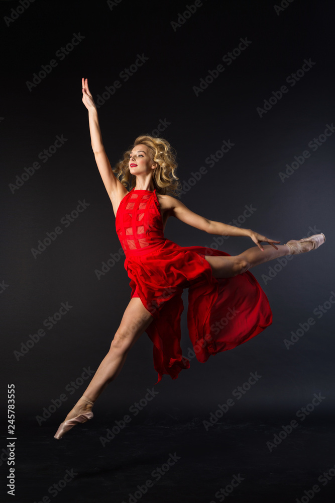 beautiful young girl in red dress jumping in ballet pose on black background beautiful young girl in red dress jumping in ballet pose on black background