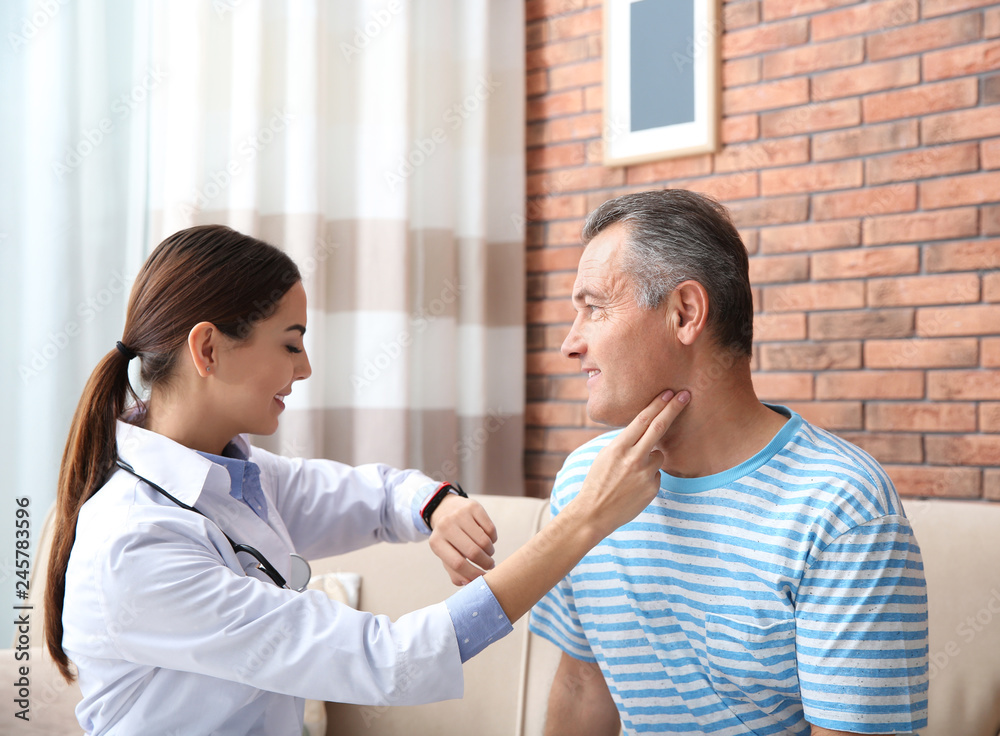 Doctor checking mature man's pulse with fingers at home Doctor checking mature man's pulse with fingers at home