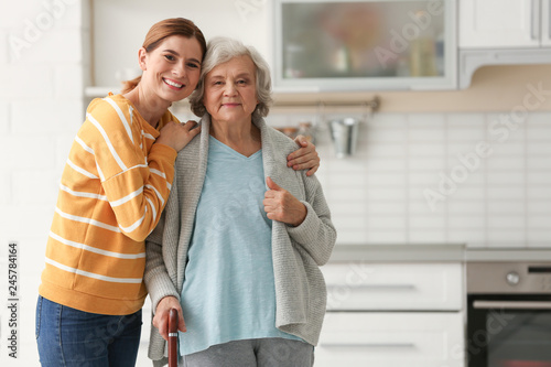 Elderly woman with female caregiver in kitchen. Space for text photo