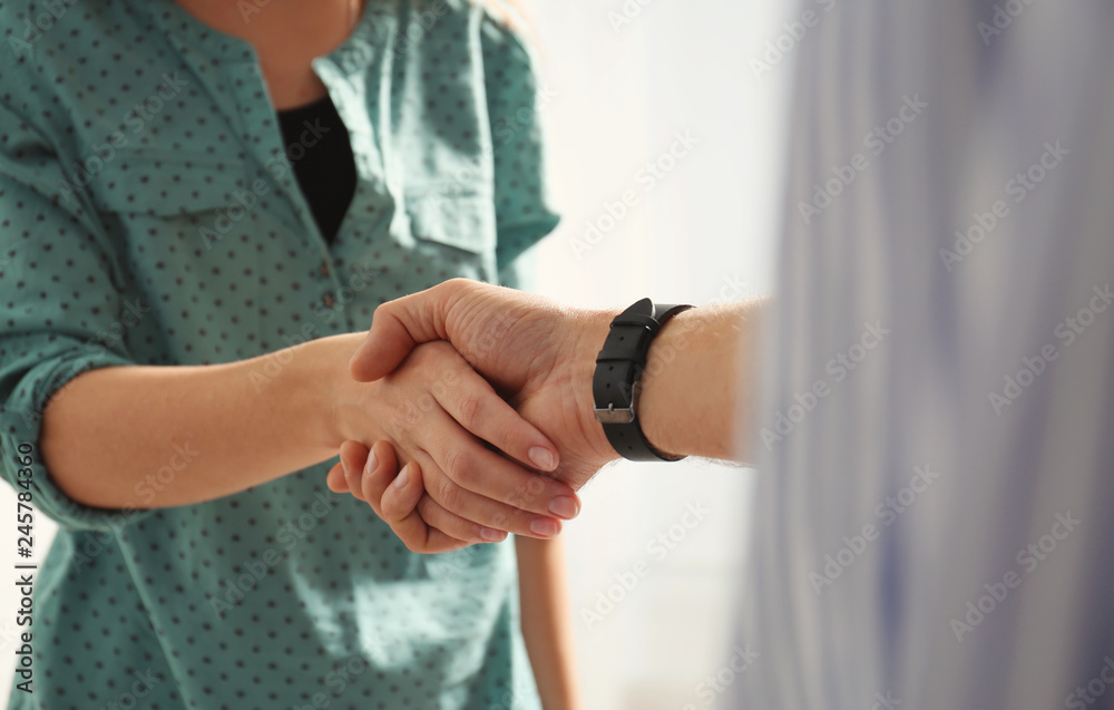 Man and woman shaking hands on light background, closeup. Help and support concept