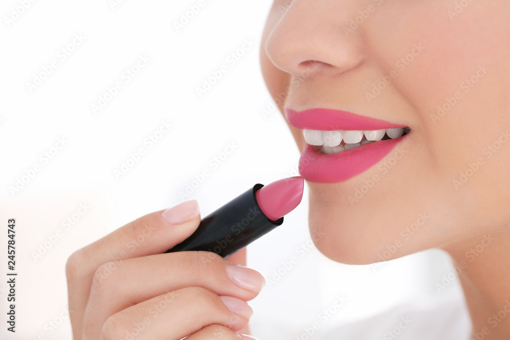 Beautiful woman applying lipstick on light background, closeup Beautiful woman applying lipstick on light background, closeup