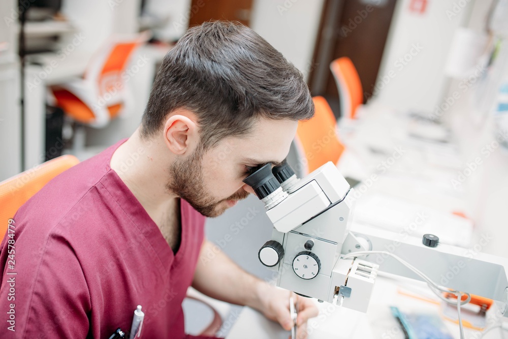male doctor examines a sample with a microscope at a medical research center. male doctor examines a sample with a microscope at a medical research center.