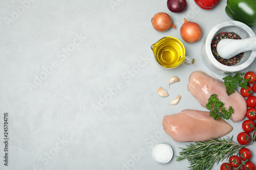 Flat lay composition with raw chicken breasts, products and space for text on gray background. Fresh meat