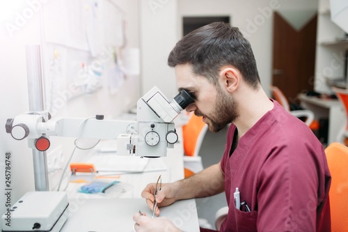 male doctor examines a sample with a microscope at a medical research center.