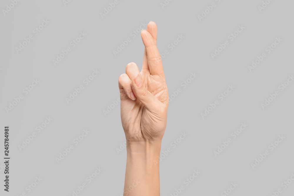 Woman showing R letter on grey background, closeup. Sign language