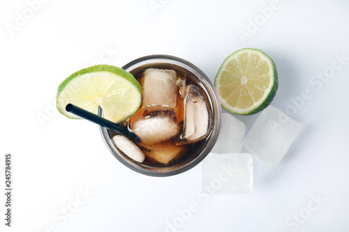 Photography Glass of cocktail with cola, ice and cut lime on white background, top view
