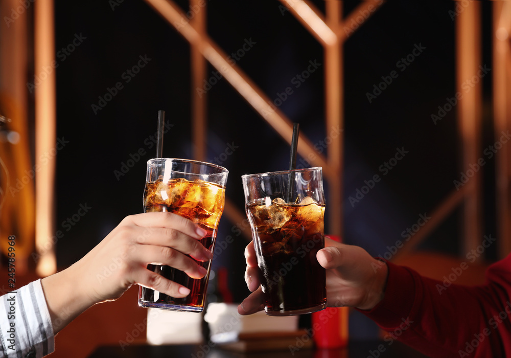 Young couple with glasses of refreshing cola at table indoors, closeup Young couple with glasses of refreshing cola at table indoors, closeup