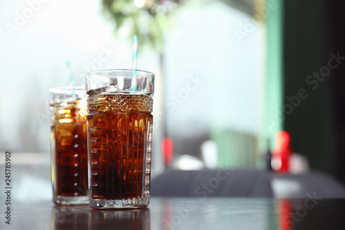 Glasses with refreshing cola and ice cubes on table indoors. Space for text