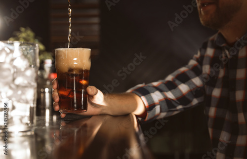 Man with glass of refreshing cola at bar counter  closeup. Pouring beverage