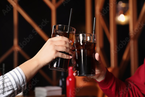 Young couple with glasses of refreshing cola indoors  closeup