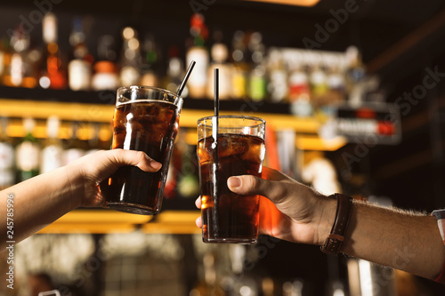 Young couple with glasses of cola in bar, closeup