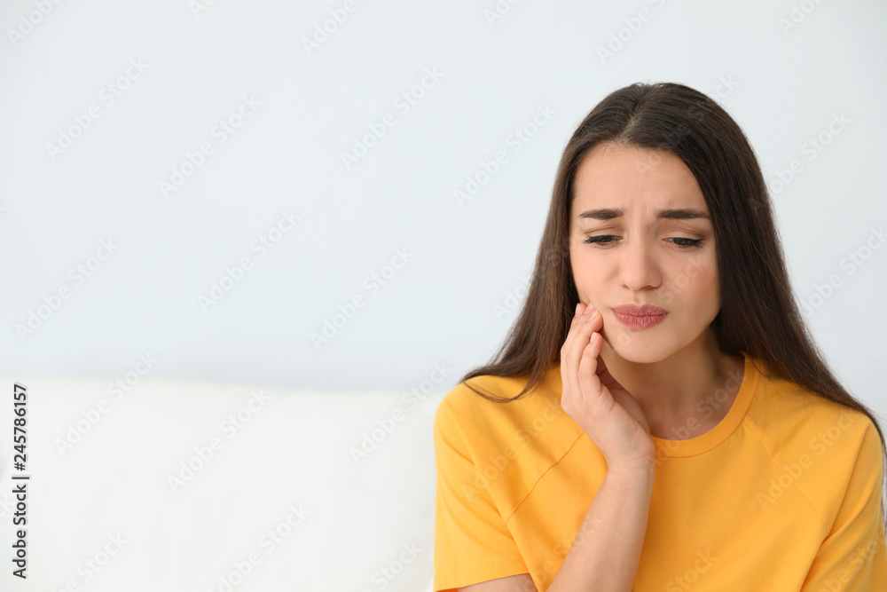 Young woman suffering from strong tooth pain at home, space for text Young woman suffering from strong tooth pain at home, space for text