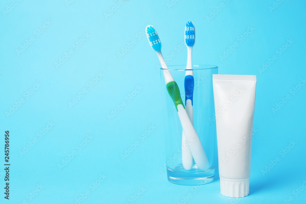 Glass with brushes and toothpaste on color background. Space for text Glass with brushes and toothpaste on color background. Space for text