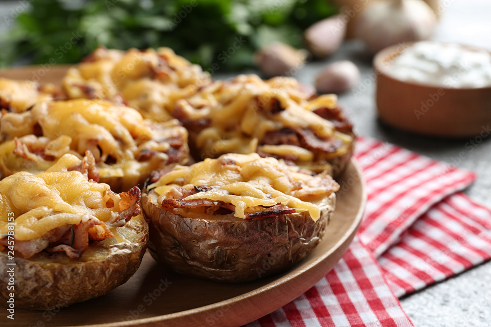 Plate of baked potatoes with cheese and bacon on table, closeup
