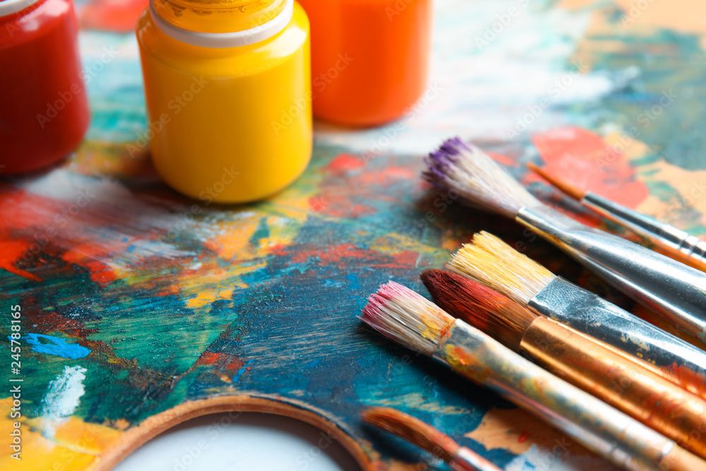 Obraz premium Different brushes and jars with paint on palette, closeup